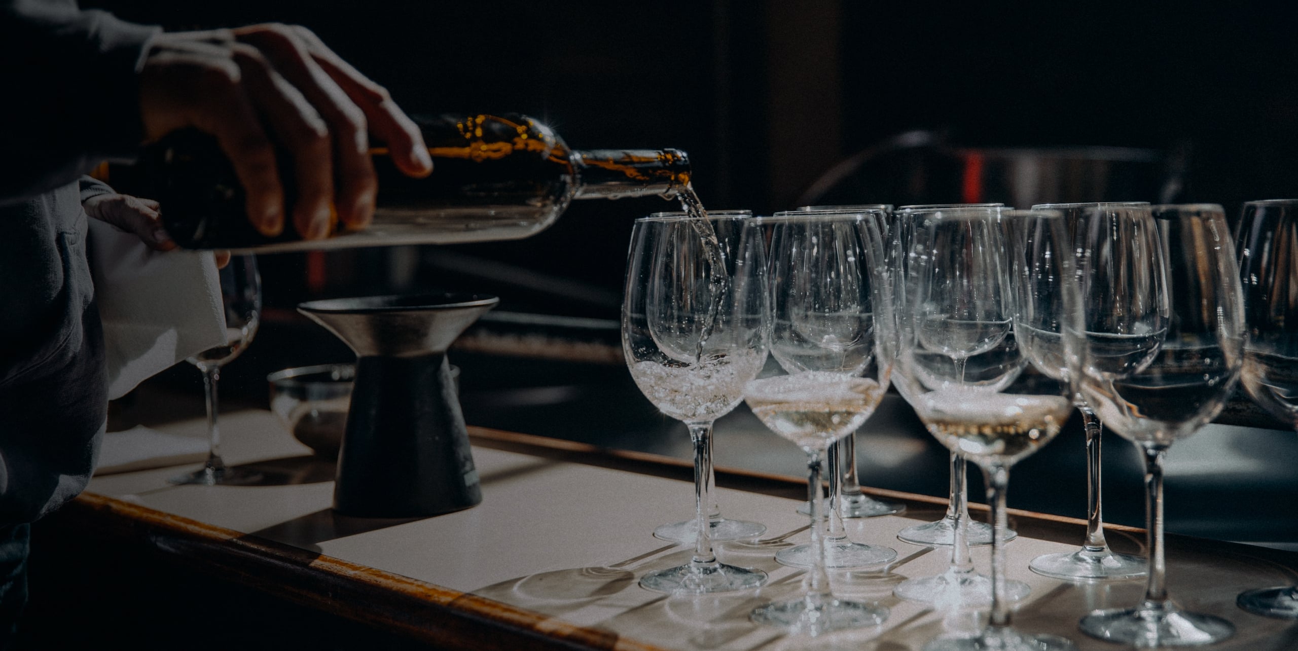 A waiter filling up some wine glasses